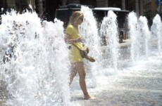 Una turista si rinfresca nella fontana di piazza De Ferrari a causa del gran caldo in una foto d'archivio.