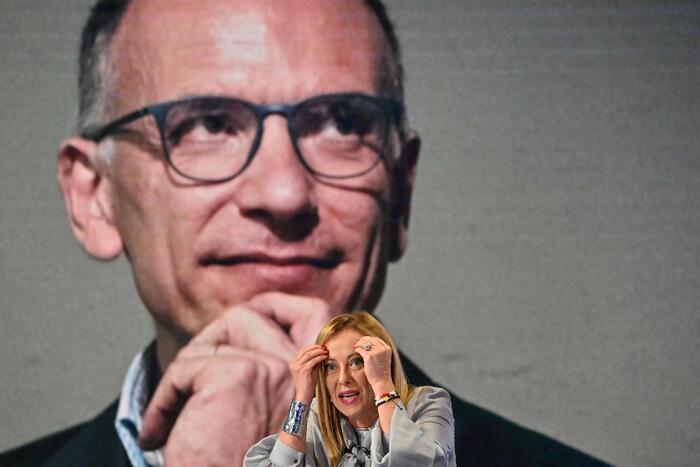 Giorgia Meloni interviene nel programma Porta a porta". Sullo sfondo l'immagine di Enrico Letta.
