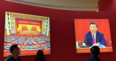 In una foto dell'Ufficio Stampa persone guardano per strada uno schermo gigante con Xi Jinping.