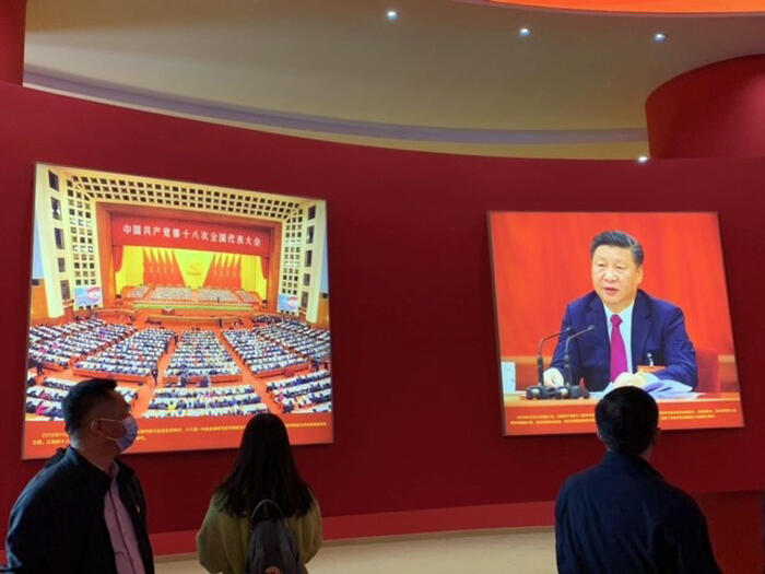 In una foto dell'Ufficio Stampa persone guardano per strada uno schermo gigante con Xi Jinping.
