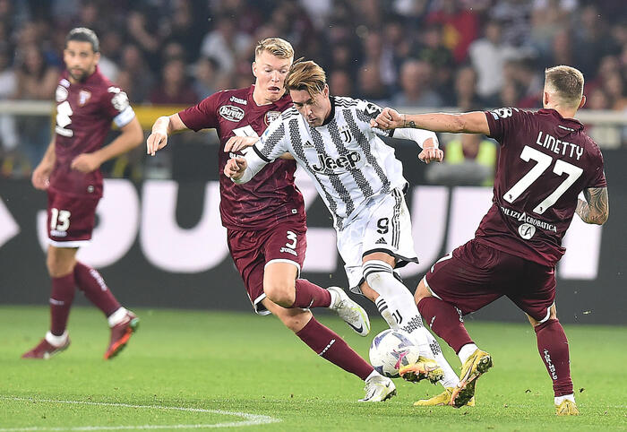 Dusan Vlahovic in azione tra due avversari nel derby vinto dalla Juventus con un suo gol.