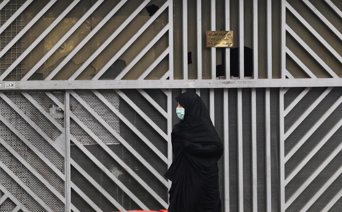 Una donna cammina di fronte ad una serranda chiusa di un negozio a Teheran.EPA/STR